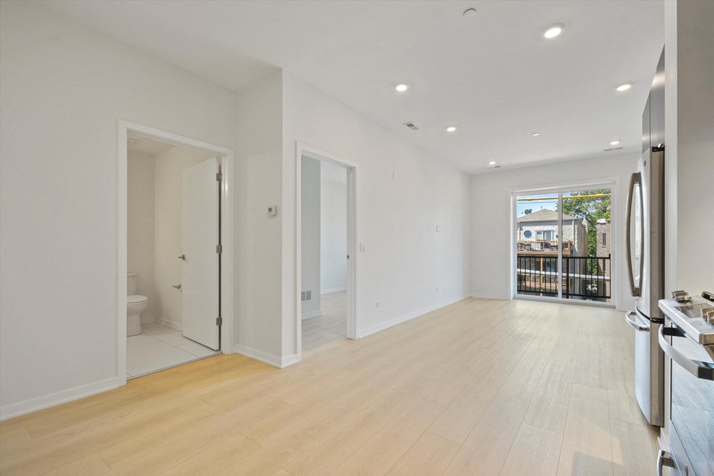 a living room with white walls and a door leading to a bathroom