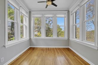 an empty room with five windows and a ceiling fan
