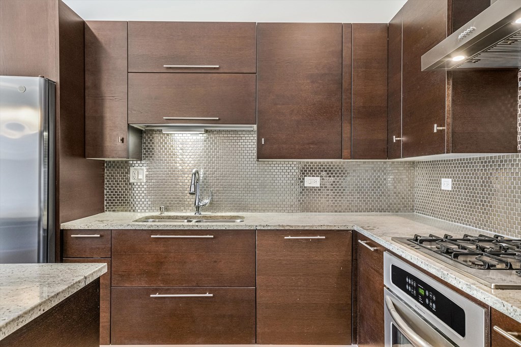 A kitchen with brown cabinets and a stainless steel refrigerator.