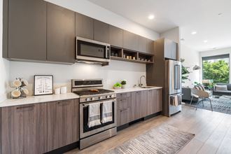 A kitchen with wooden grey cabinets and brand new stainless steel appliances