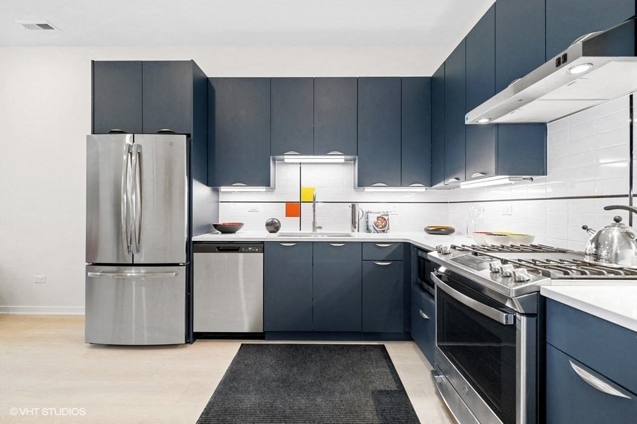 a kitchen with dark blue cabinets and stainless steel appliances