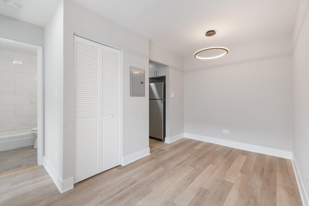 a bedroom with a medium hardwood floor and a doorway leading to a bathroom