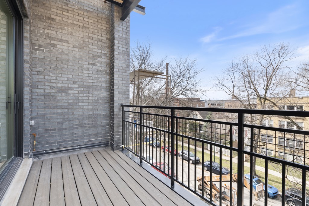 the deck of a condo balcony with a brick building in the background