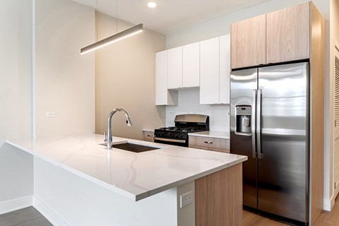 A modern kitchen with a stainless steel refrigerator and a white countertop.