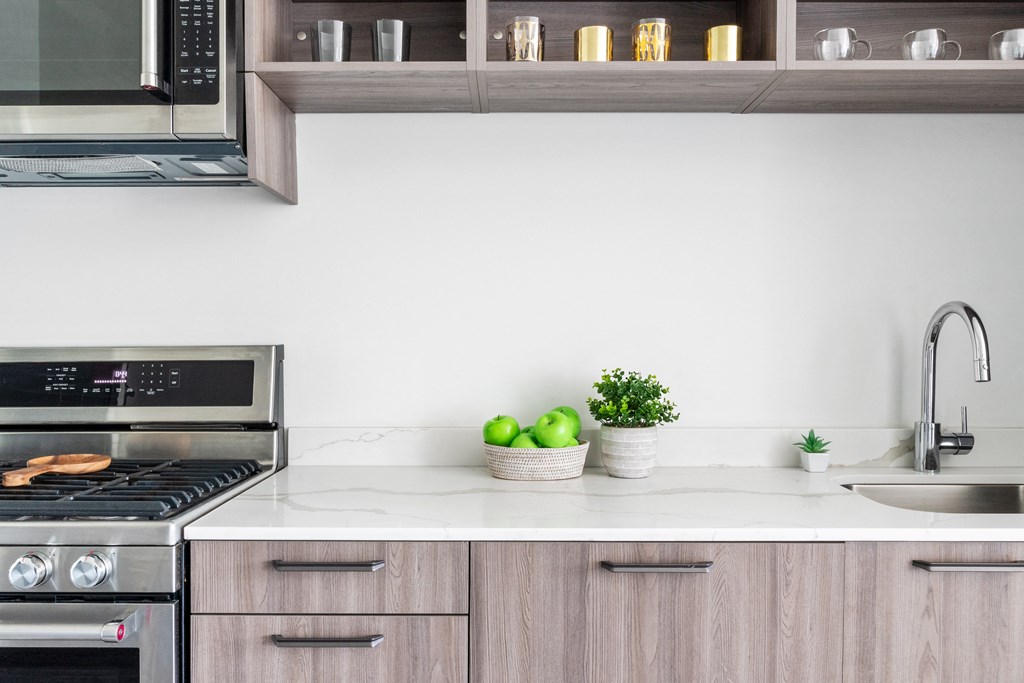 A close up of a kitchen with wooden cabinets and a white counter top