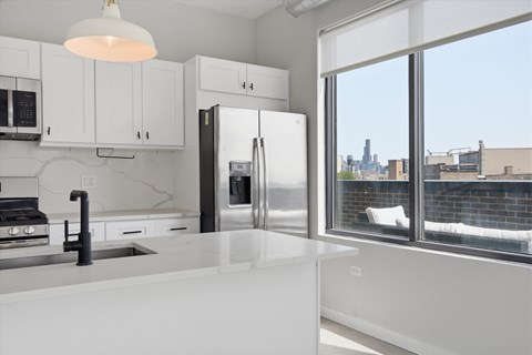 A modern kitchen with white cabinets and a view of the city.