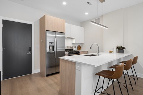 A modern kitchen with a white countertop and brown chairs.