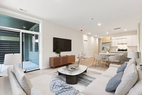 A modern living room with a flat screen TV and a glass door leading to a balcony.