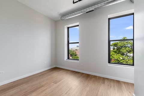 A room with two windows and a wooden floor.