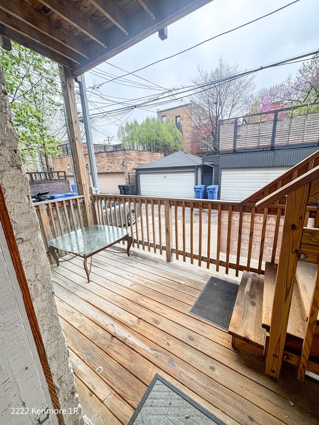 A wooden deck with a glass table and a metal railing.