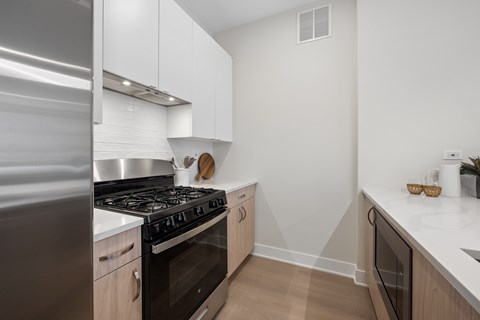 A modern kitchen with a stainless steel refrigerator and a black stove top oven.