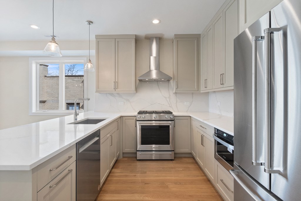 a white kitchen with stainless steel appliances and white counter tops