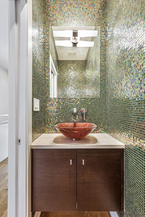 A bathroom with a brown counter top and a red bowl on it.