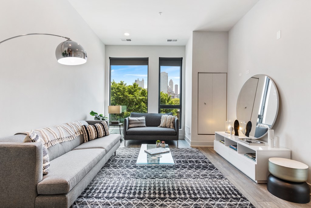 A modern living room with a cozy  grey couch, modern floor lamp, and large windows