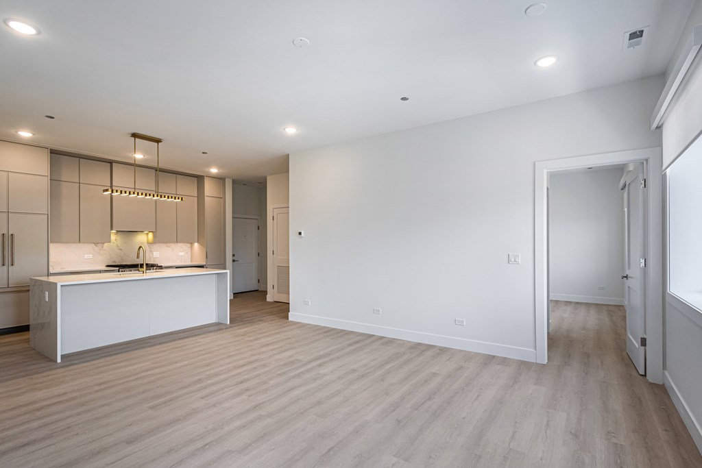 A modern kitchen with a white countertop and wooden flooring.
