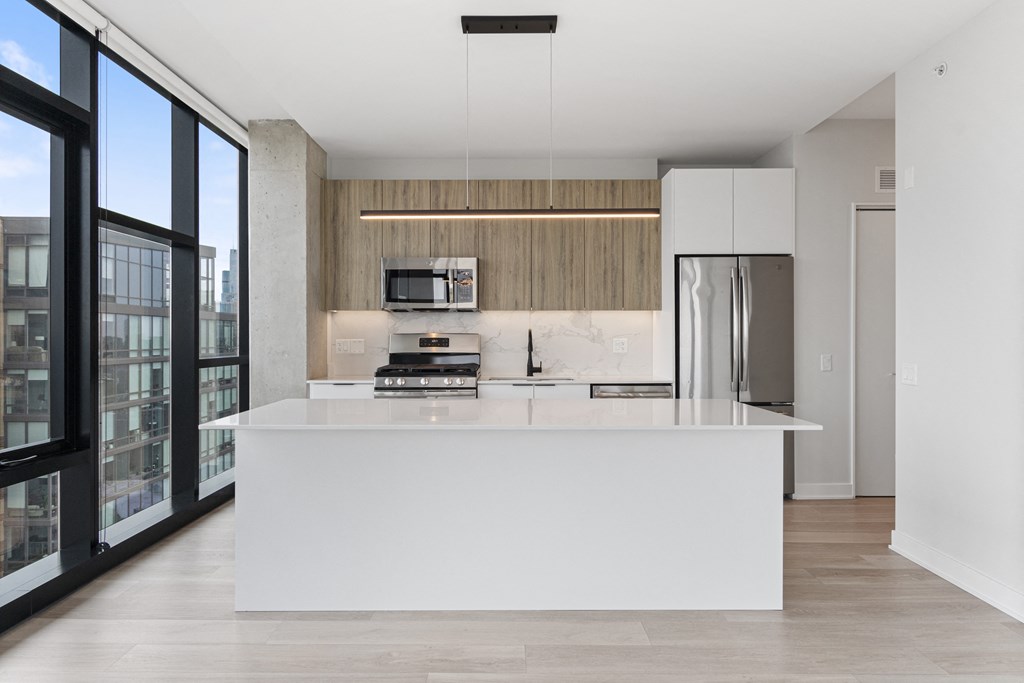 a white kitchen with a large island and stainless steel appliances