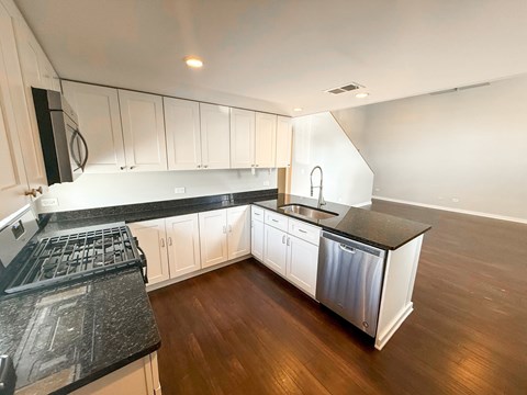 A kitchen with white cabinets and black countertops.