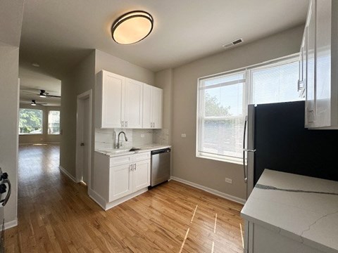A kitchen with white cabinets and a black fridge.