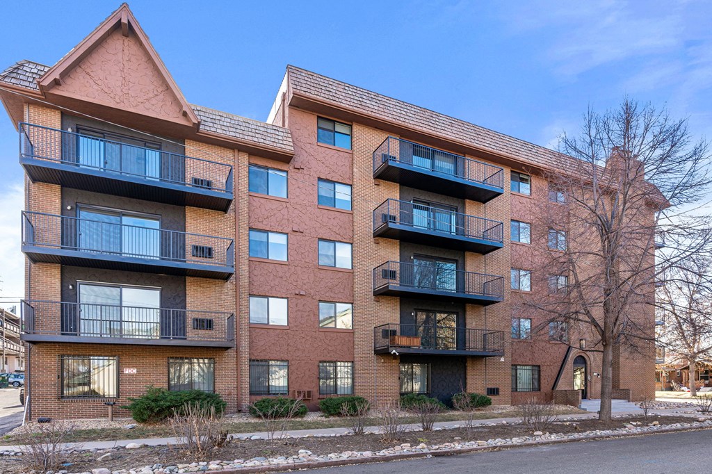 a brick apartment building with balconies and a blue sky