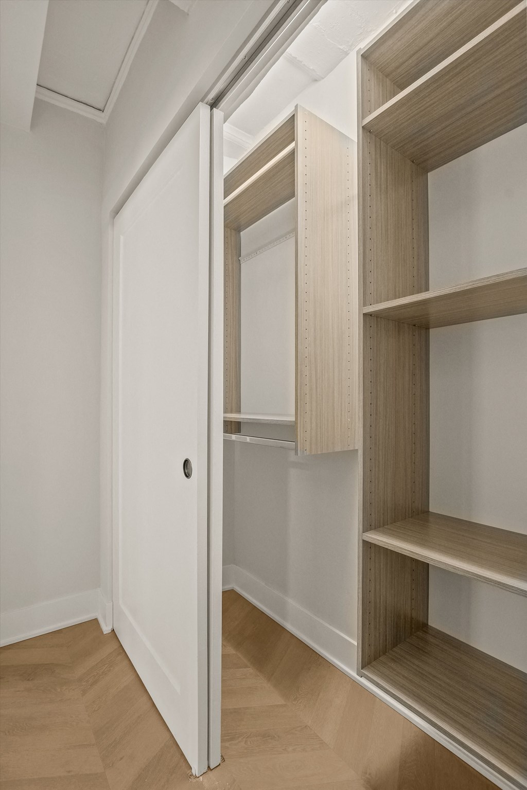 a walk in closet with a sliding door and wooden shelves