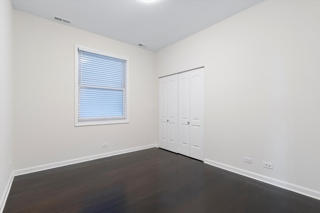 a bedroom with hardwood floors and white walls