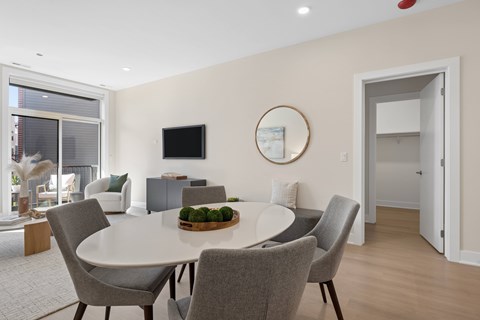 A modern dining room with a round table and grey chairs.