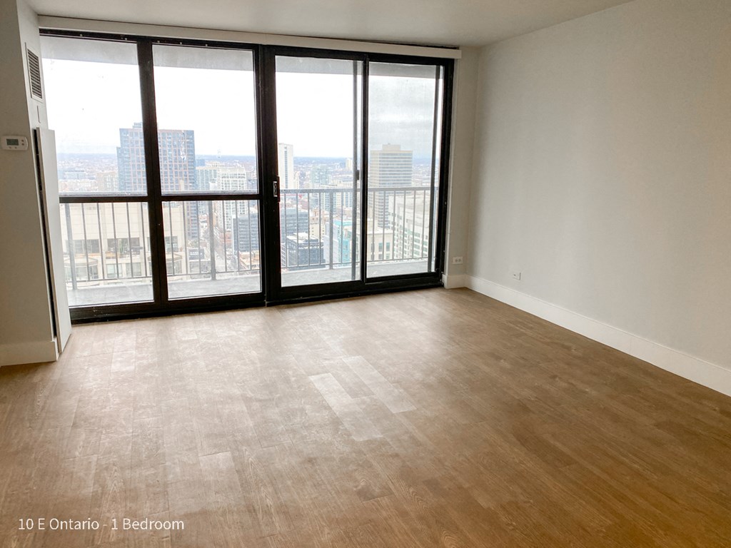 an empty living room with wood floors and a large window