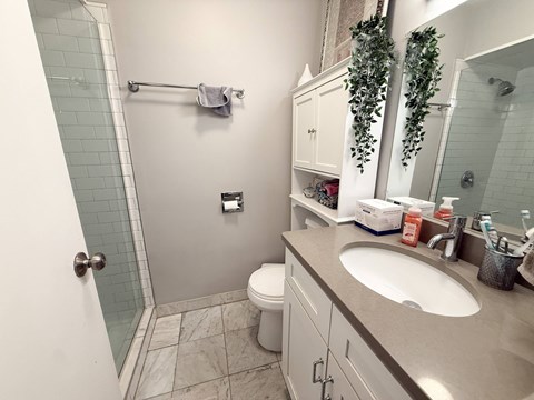 A bathroom with a toilet, sink, and a shower with a glass door.