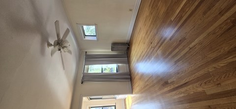 A ceiling fan is mounted on a wall in a room with wooden walls and ceiling.