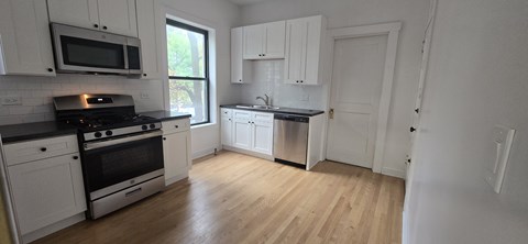 A kitchen with white cabinets and black countertops.