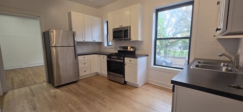 A kitchen with a stainless steel refrigerator and a window.