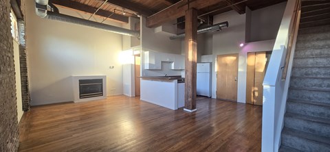 A large open room with a fireplace and wooden floors.