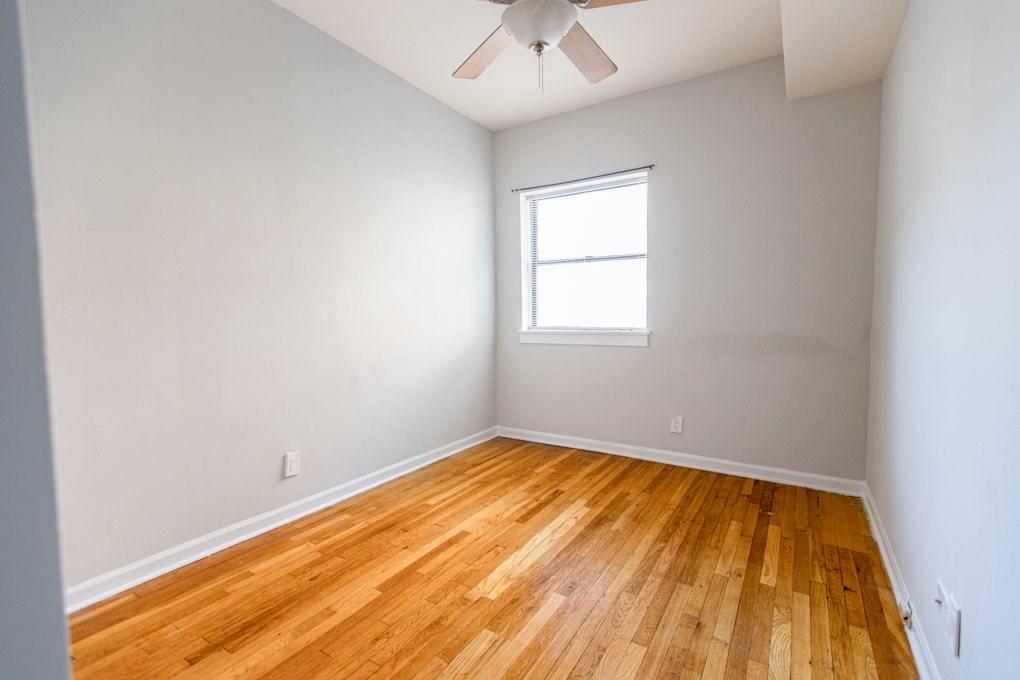 A room with a wooden floor and a ceiling fan.