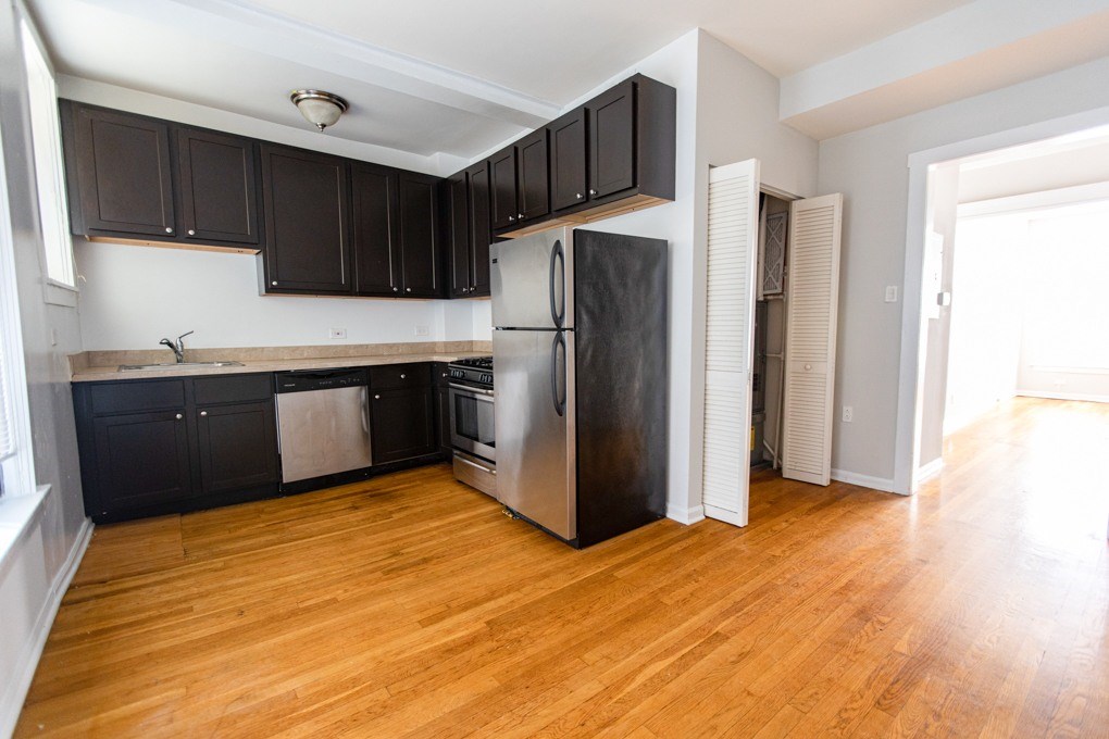 A kitchen with black cabinets and a stainless steel refrigerator.