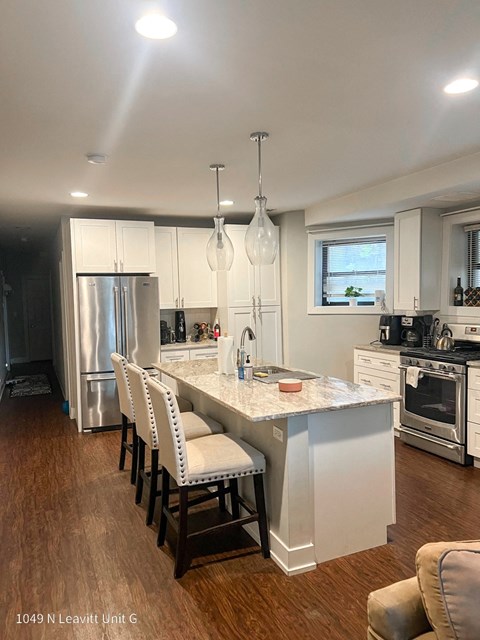 a kitchen with white cabinets and a marble counter top