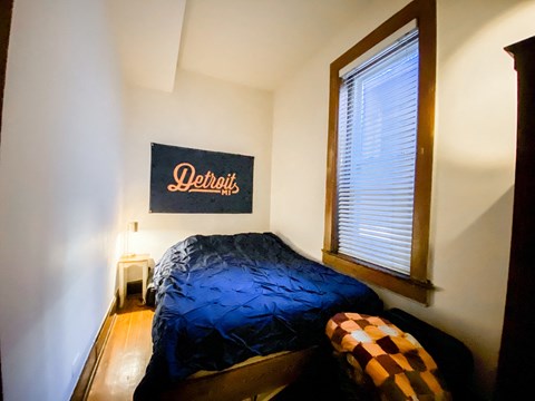 A bedroom with a bed and a Detroit sign on the wall.