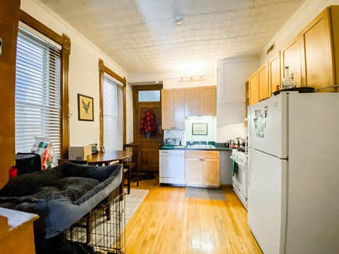 A kitchen with a white refrigerator and wooden floors.