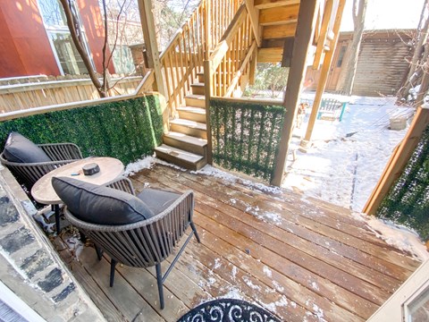 A wooden deck with a green wall and a staircase.