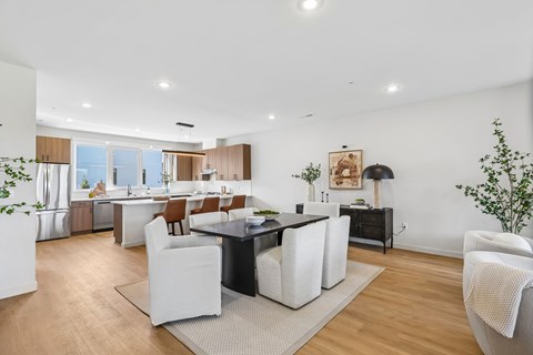 A modern kitchen with white chairs and a black table.