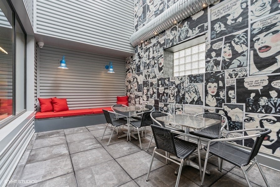 a patio with tables and chairs and a wall covered in graffiti