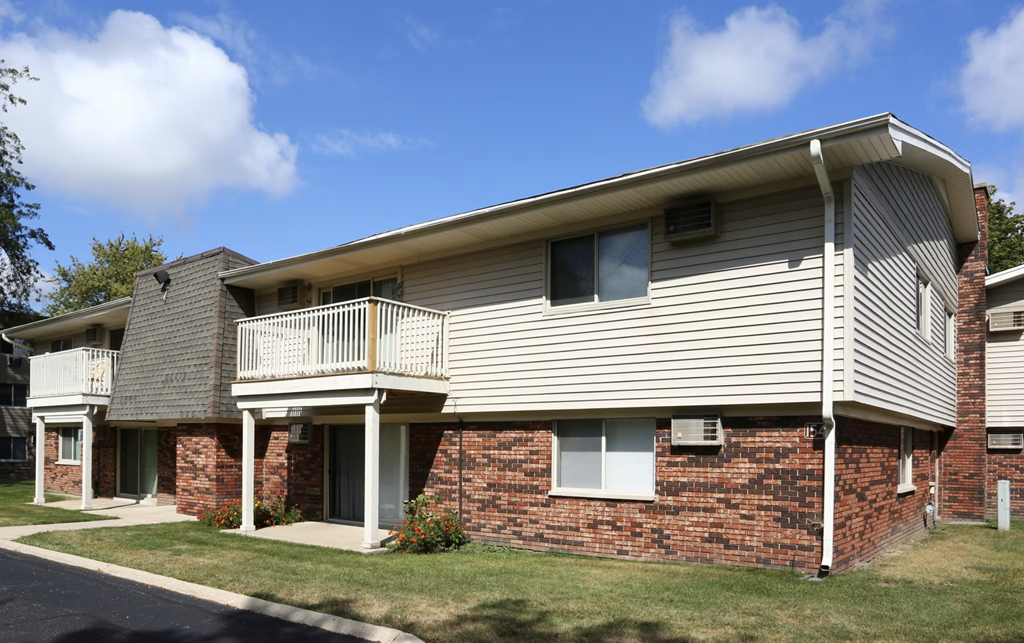 the front of a brick and white building with a balcony