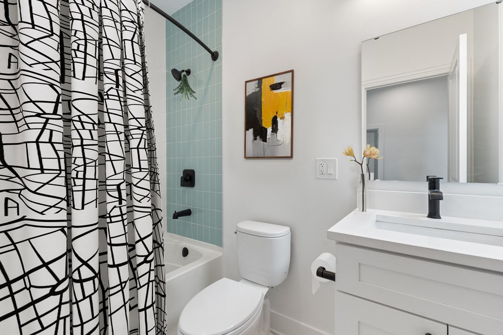 a white bathroom with a black and white shower curtain