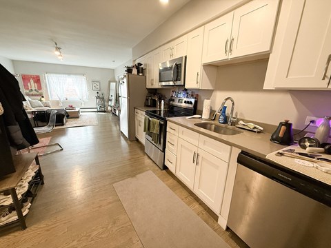 A kitchen with white cabinets and a black dishwasher.