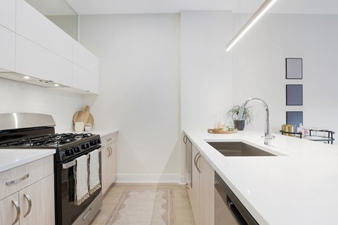 A modern kitchen with a black stove and white cabinets.