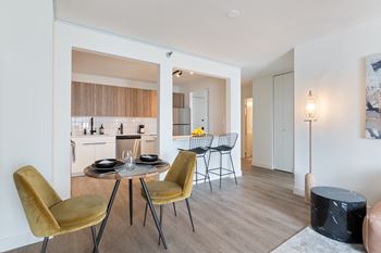 a dining area with a table and chairs and a kitchen in the background