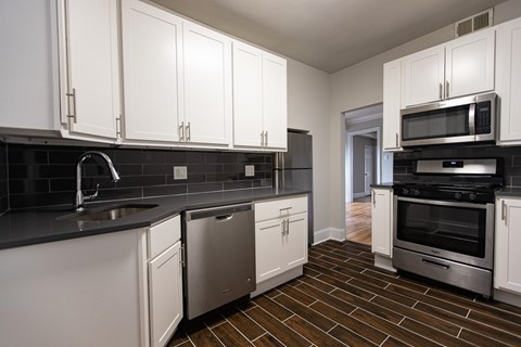 A kitchen with white cabinets and black countertops.