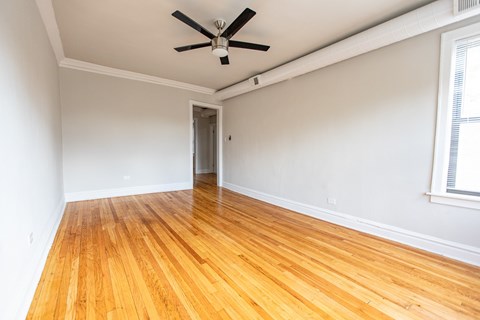 A room with a ceiling fan and wooden flooring.