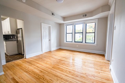 A room with wooden flooring and a window with a view of trees.