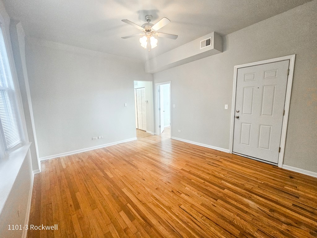 an empty living room with wood floors and a ceiling fan