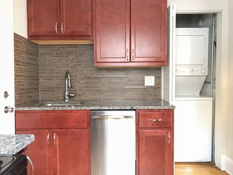an empty kitchen with red cabinets and a stainless steel dishwasher